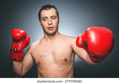 Funny Boxer Man In Knockout Over Dark Gray Background. Comic Weak Fighter With Red Sport Boxing Gloves. Waist Up Humorous Kickboxer