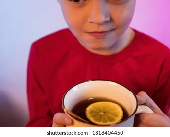 Funny Boy Blond Got Sick And Is At Home In Quarantine. Child Drinks Hot Tea From Large Bright Mug. In Cup Of Tea With Lemon And Honey. Baby Wants To Get Well Soon