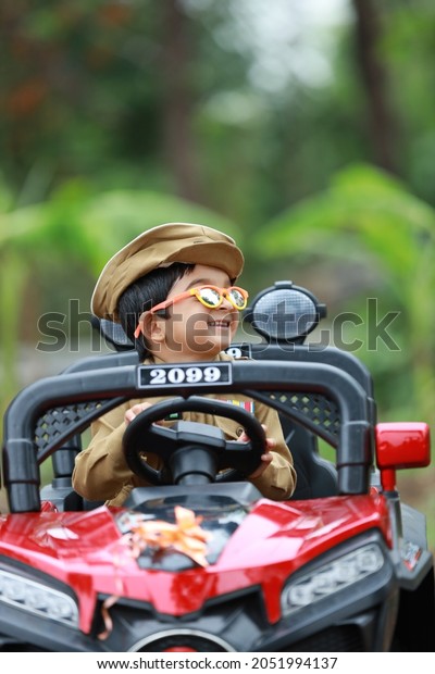 Funny boy car driver. year-old boy in a police uniform
in a red toy car outdoors. Young kid portrait with toy car, Indian
police uniform 