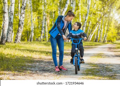 Funny Boy Cyclist Learning To Ride A Bike With Mom In The Sunny Forest On A Bike. Adventure Travel.