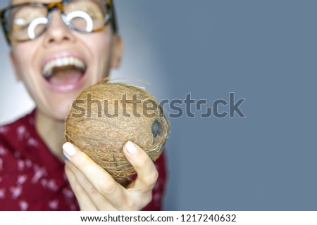 Funny boy girl holding coconut with open mouth over grey background, copy space