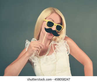 A Funny Bride With A Vintage White Dress Is Holding A Mustache Photo Booth Prop For A Humor Or Love Concept.