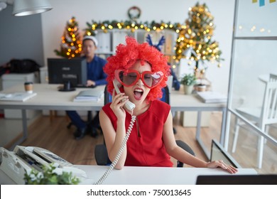 Funny business lady in bright red wig and glasses calling on the phone - Powered by Shutterstock