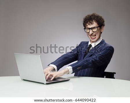 Funny business man geek using laptop with evil genius facial expression