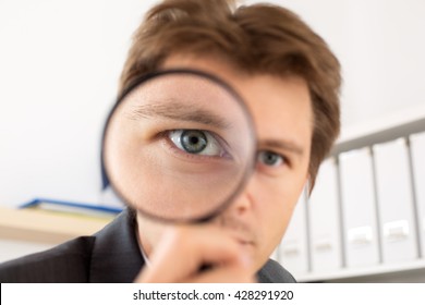 Funny Business Man Holding Magnifying Glass Portrait. Private Detective Investigation, Layer, Crime, Business Research Or Security Concept. Big Eye Through Zoom Lens.