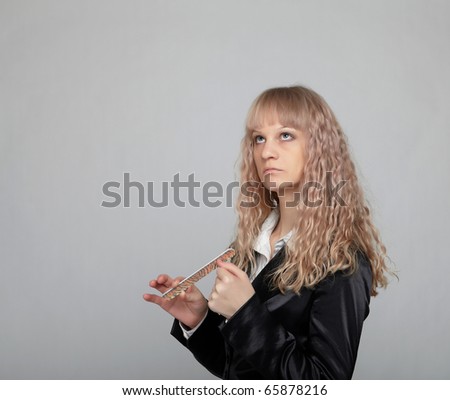 Funny business woman in a black suit with a gray background polishes nails nail file