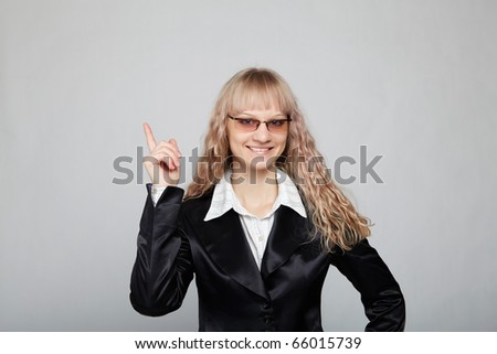 Funny business woman in a black suit with a gray background makes various hand gestures