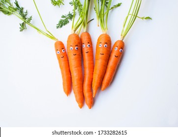 Funny carrots with faces. Creative fresh vegetable background.