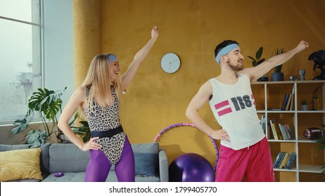 Funny Caucasian Retro Couple Doing Warm-up Aerobics Exercises Together. Female And Male Fitness Lovers Working Out Training At Home In Stylish Vintage Apartment.