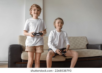 Funny caucasian siblings passionately playing video games in front of tv, two brother sister expressing emotions while enjoying their hobby playstation joystick. Copy space