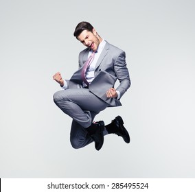Funny cheerful businessman jumping in air over gray background - Shutterstock ID 285495524