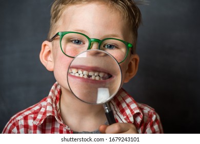 Funny Child Boy Smiling With Missing Milk Tooth. School Kid Showing Missing Tooth Through Magnifier