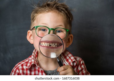 Funny Child Boy Smiling With Missing Milk Tooth. School Kid Showing Missing Tooth Through Magnifier