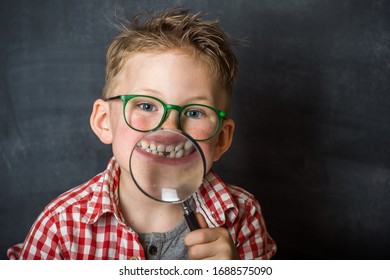 Funny Child Boy Smiling With Missing Milk Tooth. School Kid Showing Missing Tooth Through Magnifier