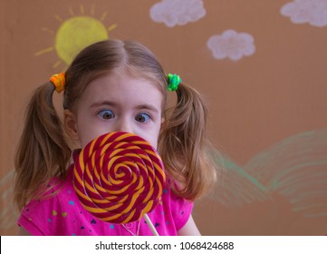 Funny child with candy lollipop, happy little girl eating big sugar lollipop, kid eat sweets.