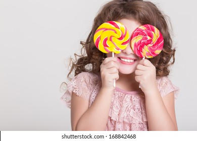 Funny child with candy lollipop, happy little girl eating big sugar lollipop, kid eat sweets. surprised child with candy. isolated on white background, studio. 