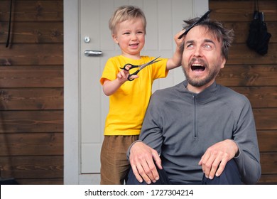 Funny Child Cutting Hair To His Father At Home During Quarantine Lockdown. Little Hairdresser Barber Makes Haircut To His Scared Bearded Dad. Beauty And Selfcare At Home Lifestyle Concept.