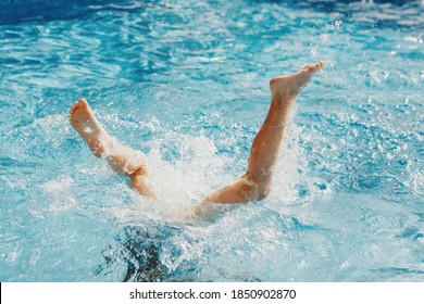 Funny Child Diving In Swimming Pool On Home Backyard. Kid Child Enjoying Having Fun In Water. Summer Outdoor Water Activity For Kids. Legs Up In The Air In Pool.