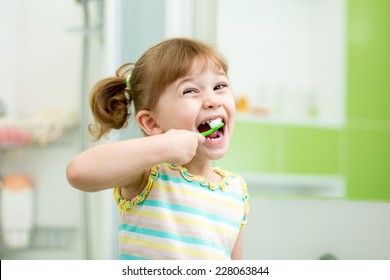 Funny Child Girl Brushing Teeth In Bathroom