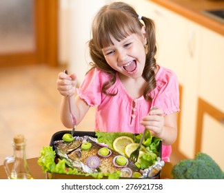 Funny Child Girl And Grilled Fish At Kitchen. Healthy Eating Seafood.