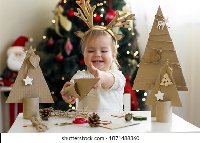 Funny child girl making decorations for christmas Handmade Christmas trees from natural materials. Concept of winter kids creativity and christmas crafts, eco friendly Christmas tree  - Powered by Shutterstock