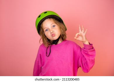 Funny Child Girl Portrait With Sign Ok Isolated On Pink Background. Kid In Safe Helmet Ready To Go On Trip. Kindergarten Kid Protect. Back To Go To School. Sport