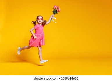 funny child girl runs and jumps with bouquet of flowers on a colored background