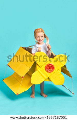 Funny child have good imagination and fantasy, want to be pilot. Portrait isolated over blue background