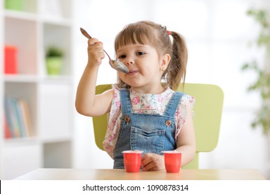 Funny Child Toddler Eating Yoghurt With A Spoon At Home