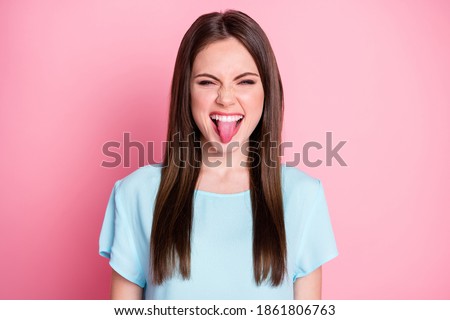 Funny childish lady sticking tongue out mouth wear casual blue t-shirt isolated pink pastel color background