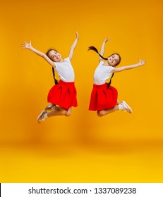 Funny Children Girls Twins Jumping On A Colored Yellow Background