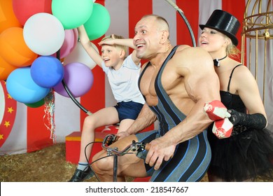 Funny circus family riding on retro bike with balloons in striped tent