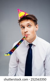 Funny Close Up Picture Of Young Office Manager With Party Hat And Blower