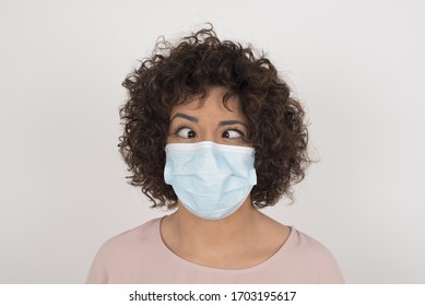 Funny Comic Girl Wearing Face Mask Crosses Eyes, Puts Lips, Makes Grimace, Foolishes After All Day Studying. Clueless Woman Nerd With Awkward Expression Has Fun Alone, Plays Fool.