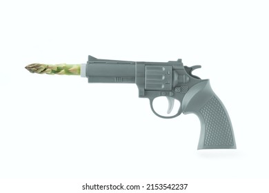 Funny Concept With Gun And Bullet Of Asparagus Officinalis On Isolated Pastel White Background. Healthy Food Diet. Abstract Creative Idea Of Green Agenda, Peace, Tolerance, Non-violence. Stop The War.