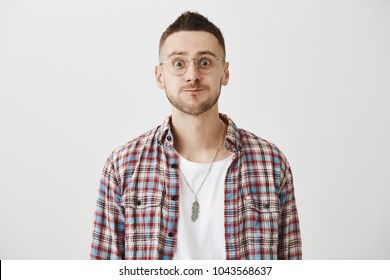 Funny Confused Caucasian Student In Glasses, Smiling Weirdly And Staring With Popped Eyes As If Being In Awkward Situation. Boyfriend Came To Dinner With Girlfriend But Met His Ex. Emotions Concept