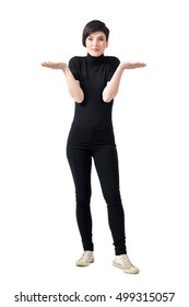 Funny Confused Clueless Young Woman In Black Turtleneck And Pants Shrugging Shoulders. Full Body Length Portrait Isolated Over White Studio Background.