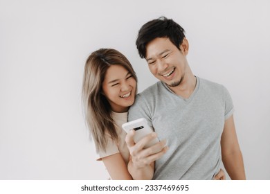 Funny couple asian lover laugh at the clip in the smartphone isolated on white. - Powered by Shutterstock