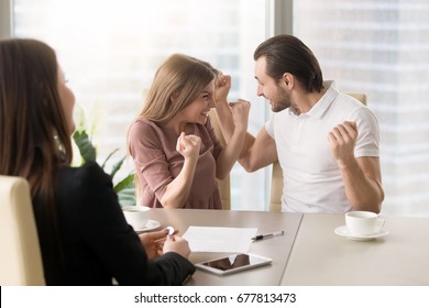 Funny couple excited by purchasing real estate meeting with agent to get the keys, delighted young family enjoys buying first apartment, achieving goal, affordable property, home loan with low rates