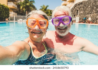 Funny couple of mature people take selfie picutre while enojy and have fun at the pool in residence - elderly retired happy lifestyle with aged couple in summer leisure activity together - Powered by Shutterstock