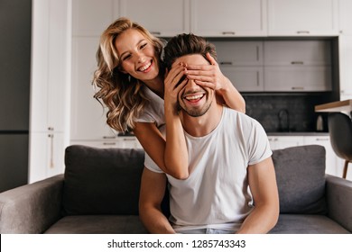 Funny Couple Playing Seek And Hide. Curly Girl Sitting On Sofa With Boyfriend.