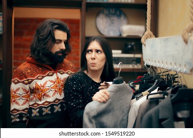 Funny Couple Shopping For Clothes In Sale Season. Husband And Wife Checking Price Tag On Expensive, Clothing Item
