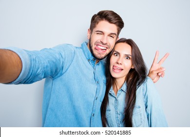 Funny couple showing tongues and gesturing v-sign while making selfie.