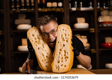 Funny crazy cheese sommelier with 2 pieces of limited maasdam natural aged between his head. Creative worker of cheese food shop smiling, laughing and having fun