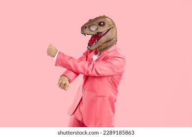Funny crazy man with mask lizard or dinosaur head dancing isolated on pink background. Man in pink suit puts on animal's head and has fun during costume party. Creative concept for advertising. - Shutterstock ID 2289185863