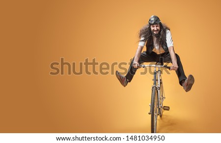 Funny crazy man riding a bike, on studio background