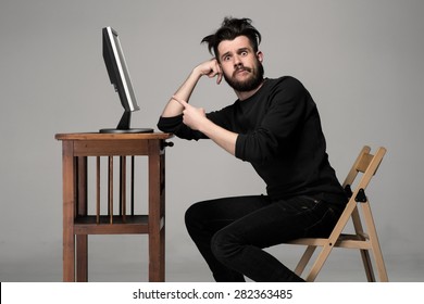 Funny and crazy man using a computer on gray background. man's hand pointing at the monitor. Concept of surprise and indignation