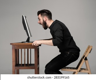 Funny and crazy man using a computer on gray background. man's hands on thetable. Concept of surprise and indignation