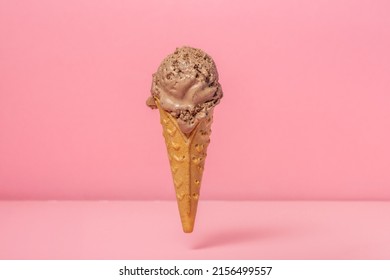 funny creative concept of hovering in air wafer cone with chocolate ice cream scoop on pink background