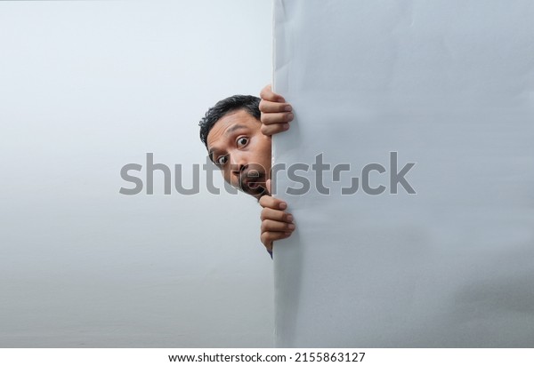 funny curious man\
peeking behind the wall